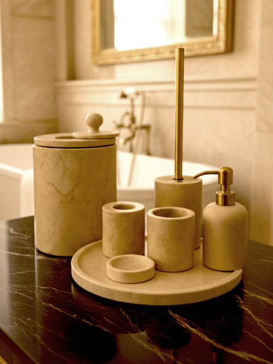 Luxury Toros beige gold marble bathroom accessory set with gold accents displayed on a dark marble countertop, featuring lotion dispenser, cotton jar, toothbrush holder, soap dish, tray, waste basket, and toilet brush — handcrafted Turkish marble décor by Creative Home Designs,BAS-KRYKK-TOROS-BEIGo-S5,BAS-KRYKK-TOROS-BEIGo-S7