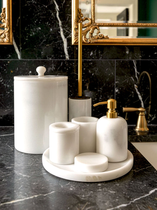 Luxury pearl white Afyon marble bathroom accessory set with gold accents displayed on a black marble countertop, featuring lotion dispenser, cotton box, toothbrush holder, soap dish, tray, waste basket, and toilet brush — handcrafted Turkish marble décor by Creative Home Designs,BAS-KRYKK-AFYON-PEARLGo-S7,BAS-KRYKK-AFYON-PEARLGo-S5