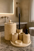 Luxury beige travertine marble bathroom accessory set displayed on a light stone countertop, featuring lotion dispenser, cotton jar, toothbrush holder, soap dish, tray, waste basket, and toilet brush — handcrafted Turkish travertine décor by Creative Home Designs.BAS-KRYKK-TRVTN-Bla-S7,BAS-KRYKK-TRVTN-Bla-S5