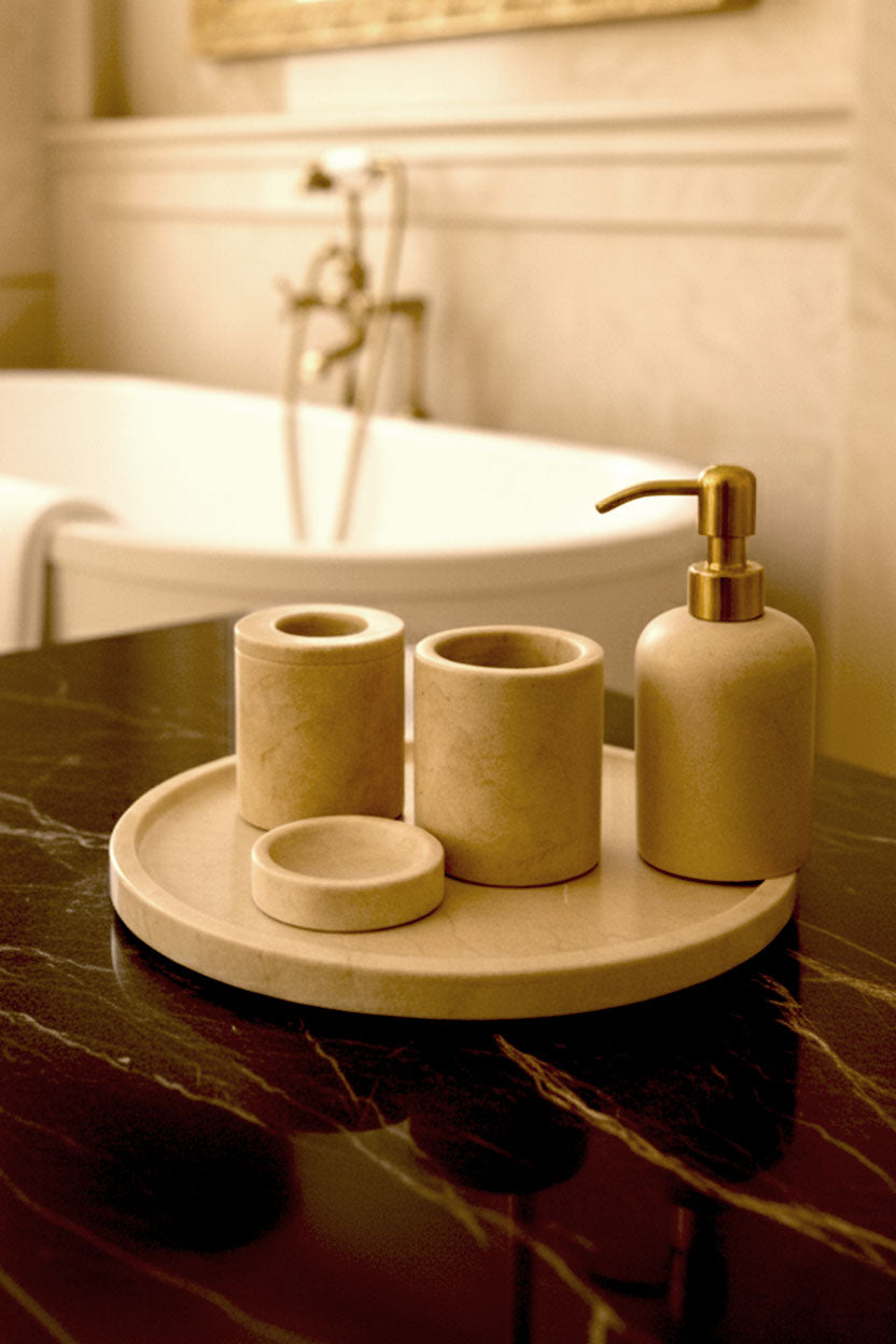 Luxury Toros beige gold marble bathroom accessory set with gold accents displayed on a dark marble countertop, featuring lotion dispenser, cotton jar, toothbrush holder, soap dish, tray, waste basket, and toilet brush — handcrafted Turkish marble décor by Creative Home Designs,BAS-KRYKK-TOROS-BEIGo-S5,BAS-KRYKK-TOROS-BEIGo-S7