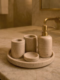 Luxury beige travertine marble bathroom accessory set displayed on a light stone countertop, featuring lotion dispenser, cotton jar, toothbrush holder, soap dish, tray, waste basket, and toilet brush — handcrafted Turkish travertine décor by Creative Home Designs.BAS-KRYKK-TRVTN-Go-S7,BAS-KRYKK-TRVTN-Go-S5