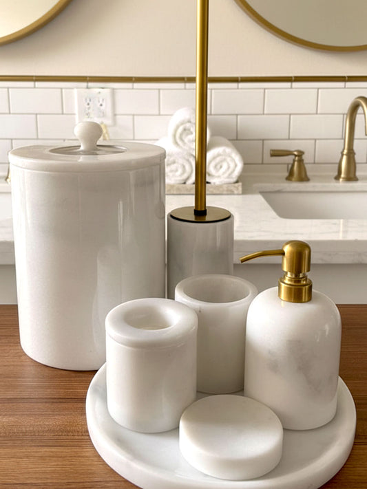 Luxury pearl white Afyon marble bathroom accessory set with gold accents displayed on a black marble countertop, featuring lotion dispenser, cotton box, toothbrush holder, soap dish, tray, waste basket, and toilet brush — handcrafted Turkish marble décor by Creative Home Designs,BAS-KRYKK-AFYON-PEARLGo-S7,BAS-KRYKK-AFYON-PEARLGo-S5