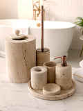 Luxury beige travertine marble bathroom accessory set displayed on a light stone countertop, featuring lotion dispenser, cotton jar, toothbrush holder, soap dish, tray, waste basket, and toilet brush — handcrafted Turkish travertine décor by Creative Home Designs.BAS-KRYKK-TRVTN-Cop-S7,BAS-KRYKK-TRVTN-Cop-S5