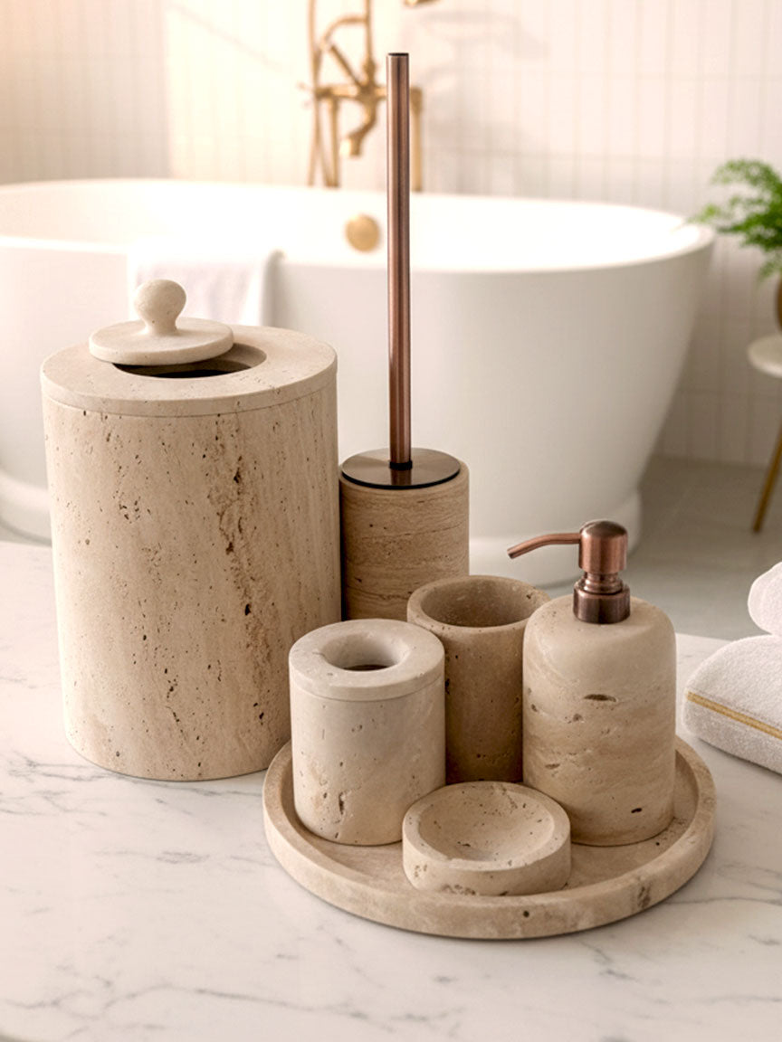 Luxury beige travertine marble bathroom accessory set displayed on a light stone countertop, featuring lotion dispenser, cotton jar, toothbrush holder, soap dish, tray, waste basket, and toilet brush — handcrafted Turkish travertine décor by Creative Home Designs.BAS-KRYKK-TRVTN-Cop-S7,BAS-KRYKK-TRVTN-Cop-S5