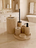 Luxury beige travertine marble bathroom accessory set displayed on a light stone countertop, featuring lotion dispenser, cotton jar, toothbrush holder, soap dish, tray, waste basket, and toilet brush — handcrafted Turkish travertine décor by Creative Home Designs.BAS-KRYKK-TRVTN-Bla-S7,BAS-KRYKK-TRVTN-Bla-S5