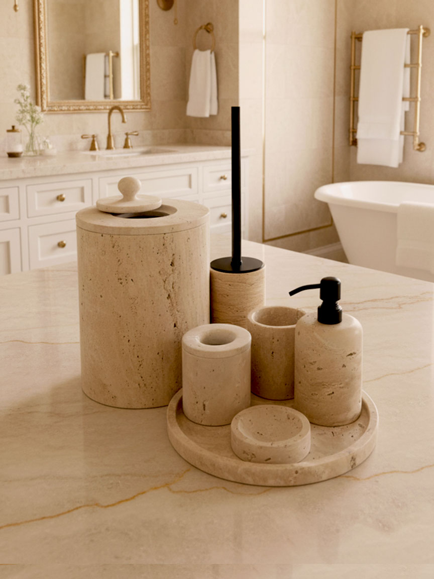 Luxury beige travertine marble bathroom accessory set displayed on a light stone countertop, featuring lotion dispenser, cotton jar, toothbrush holder, soap dish, tray, waste basket, and toilet brush — handcrafted Turkish travertine décor by Creative Home Designs.BAS-KRYKK-TRVTN-Bla-S7,BAS-KRYKK-TRVTN-Bla-S5