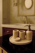 Luxury Toros beige gold marble bathroom accessory set with gold accents displayed on a dark marble countertop, featuring lotion dispenser, cotton jar, toothbrush holder, soap dish, tray, waste basket, and toilet brush — handcrafted Turkish marble décor by Creative Home Designs,BAS-KRYKK-TOROS-BEIGo-S5,BAS-KRYKK-TOROS-BEIGo-S7