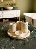 Luxury beige travertine marble bathroom accessory set displayed on a light stone countertop, featuring lotion dispenser, cotton jar, toothbrush holder, soap dish, tray, waste basket, and toilet brush — handcrafted Turkish travertine décor by Creative Home Designs.BAS-KRYKK-TRVTN-Bla-S7,BAS-KRYKK-TRVTN-Bla-S5