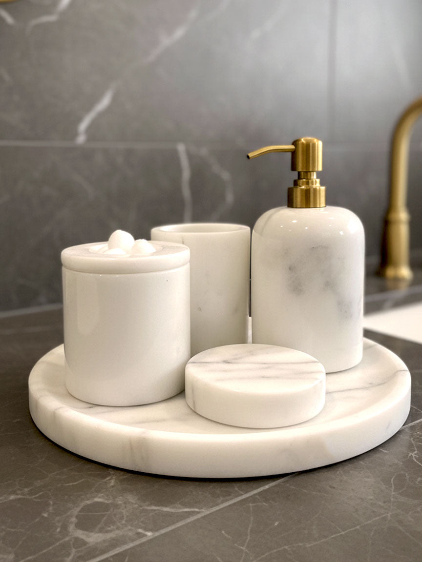 Luxury pearl white Afyon marble bathroom accessory set with gold accents displayed on a black marble countertop, featuring lotion dispenser, cotton box, toothbrush holder, soap dish, tray, waste basket, and toilet brush — handcrafted Turkish marble décor by Creative Home Designs,BAS-KRYKK-AFYON-PEARLGo-S7,BAS-KRYKK-AFYON-PEARLGo-S5
