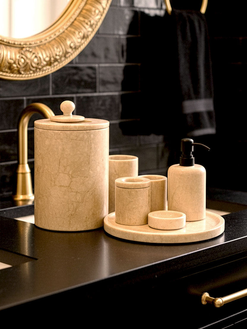 Luxury Toros beige gold marble bathroom accessory set with gold accents displayed on a dark marble countertop, featuring lotion dispenser, cotton jar, toothbrush holder, soap dish, tray, waste basket, and toilet brush — handcrafted Turkish marble décor by Creative Home Designs,BAS-KRYKK-TOROS-BEIBla-S7,BAS-KRYKK-TOROS-BEIBla-S5