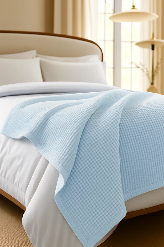 Bedroom with a neatly made bed styled with a 100% Turkish cotton waffle blanket, showing its textured waffle weave and cozy bedcover look as throw blanket by Creative Home. BB-DesH-WaBlnkt-SkBlu-6070,BB-DesH-WaBlnkt-SkBlu-Tw,BB-DesH-WaBlnkt-SkBlu-Q,BB-DesH-WaBlnkt-SkBlu-K,BB-DesH-WaBlnkt-SkBlu-100118,BB-DesH-WaBlnkt-SkBlu-100125