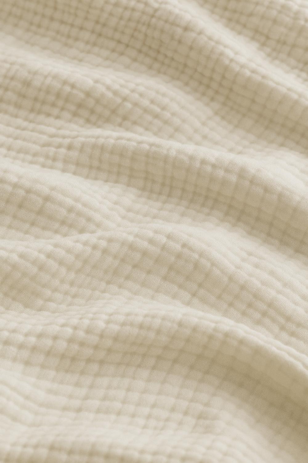 Luxury bedroom featuring a 100% muslin cotton cream gauze cloud blanket with matching pillows, styled on a bed beneath an arched window. BB-DesH-Blnkt-Cr-6070,BB-DesH-Blnkt-Cr-Tw, BB-DesH-Blnkt-Cr-Q,BB-DesH-Blnkt-Cr-K,BB-DesH-Blnkt-Cr-100118,BB-DesH-Blnkt-Cr-100125