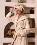 Woman wearing a beige Bamboo bathrobe by Creative Home, Gelin SPA Set with embroidery lace BRW-CH-GLNBei-Go-S-BO,BRW-CH-GLNBei-Go-S-BS,BRW-CH-GLNBei-Go-S-BST,BRW-CH-GLNBei-Go-M-BO,BRW-CH-GLNBei-Go-M-BS,BRW-CH-GLNBei-Go-M-BST,BRW-CH-GLNBei-Go-L-BO,BRW-CH-GLNBei-Go-L-BS,BRW-CH-GLNBei-Go-L-BST,BRW-CH-GLNBei-Go-XL-BO,BRW-CH-GLNBei-Go-XXL-BO,BRW-CH-GLNBei-Go-XXXL-BO,BRW-CH-GLNBei-Go-XL-BS,BRW-CH-GLNBei-Go-XXL-BS,BRW-CH-GLNBei-Go-XXXL-BS,BRW-CH-GLNBei-Go-XL-BST,BRW-CH-GLNBei-Go-XXL-BST,BRW-CH-GLNBei-Go-XXXL-BST